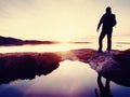 Hiker in dark sportswear with poles and sporty backpack. Coastline trail on rocky shore. Alone tourist enjoy Royalty Free Stock Photo