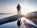 Hiker in dark sportswear with poles and sporty backpack. Coastline trail on rocky shore. Alone tourist enjoy Royalty Free Stock Photo