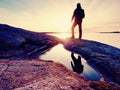 Hiker in dark sportswear with poles and sporty backpack. Coastline trail on rocky shore. Alone tourist enjoy Royalty Free Stock Photo