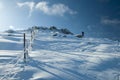 Hiker in the distance ascending next to a fence a snowy mountain in the morning