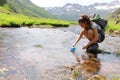 Hiker filling canteen with raw water in a river