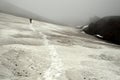 Hiker in fog and on snow, surrounded by the black lava landscape close to Tolbachik volcano in Kamchatka in Russia