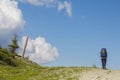 Hiker follows a path, the blue sky on the horizon. Hiking travel outdoor concept in mountains