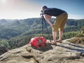 Hiker framing picture with the face on the camera on cliff