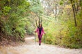 Hiker girl walking towards camera on a wide trail in the mountains. Backpacker with pink jacket in a forest. Healthy fitness Royalty Free Stock Photo