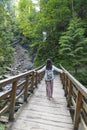 Hiker girl on a wooden bridge in front of mountain waterfall Royalty Free Stock Photo