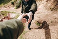 A hiker gives a hand to another person during hiking in a mountainous area.