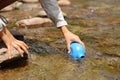 Hiker hand filling canteen with raw water from river