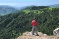 Hiker With Hat Looking Down On Trees Covered Mountains