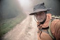 Hiker With Hat Taking A Selfie Along A Misty Path
