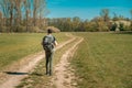 A hiker on a hike with a backpack on his back walks a dirt road towards the forest