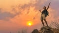 Hiker hiking success on rocky hill top at sunset