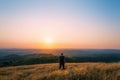 A hiker on a hill looking out across the English landscape towards the setting sun on a summers evening