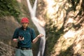 Hiker holds smartphone trying to find connection in deep forest with waterfalls. Royalty Free Stock Photo