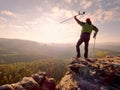 Hiker with hurts knee. Man with leg in join immobilizer stay on summit and raise medicine crutch