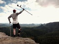 Hiker huts knee. Man with leg in join immobilizer stay on summit and raise medicine cruth above head.