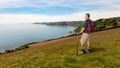 In Cornwall, England, a backpacker stands on the green above the cliffs.