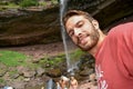 Hiker leans over to take a selfie in front of a waterfall