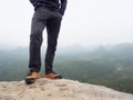 Hiker legs in comfortable trekking boots on rock. Man legs in light outdoor trousers, leather shoes Royalty Free Stock Photo