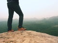 Hiker legs in comfortable trekking boots on rock. Man legs in light outdoor trousers, leather shoes Royalty Free Stock Photo