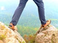 Hiker legs in comfortable trekking boots on rock. Man legs in light outdoor trousers, leather shoes Royalty Free Stock Photo