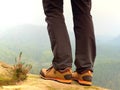 Hiker legs in comfortable trekking boots on rock. Man legs in light outdoor trousers, leather shoes Royalty Free Stock Photo