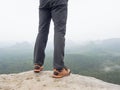 Hiker legs in comfortable trekking boots on rock. Man legs in light outdoor trousers, leather shoes Royalty Free Stock Photo