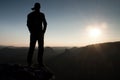 Hiker in long cap on rock empire and watching to Sun. Beautiful moment the miracle of nature Royalty Free Stock Photo