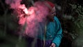 Hiker lost in the evening forest lighting a red signal flare and starting to wave his arm. Stock footage. Burning signal