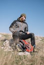 Hiker male sitting on a rock on top of the mountain