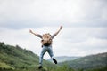A hiker man with a backpack jumps for joy of success. Finish concept