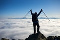 Hiker man on rocky hill on foggy valley with white clouds, snowy mountains and blue sky background. Royalty Free Stock Photo