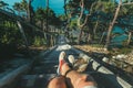 Hiker Man Sitting On Steps Of Stairs Coast Above Sea, View Of Legs. Point Of View Shot