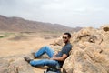 Hiker man sitting on top of a mountain in the desert Royalty Free Stock Photo