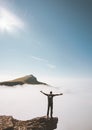 Hiker man standing alone on mountain cliff edge over clouds raised hands Royalty Free Stock Photo