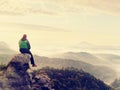 Hiker man take a rest on mountain peak. Man sit on sharp summit and enjoy spectacular view. Royalty Free Stock Photo