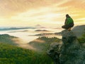 Hiker man take a rest on mountain peak. Man sit on sharp summit and enjoy spectacular view. Royalty Free Stock Photo