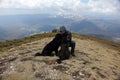 Hiker in the mountains with two black dogs