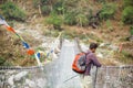 Hiker observing mountain river from suspension bridge