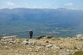 Hiker observing a village from a mountain top with a mountainous landscape in the background