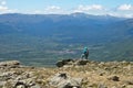 Hiker observing a village from a mountain top with a mountainous landscape in the background