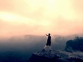 Hiker in pants is taking photo on the rocky peak at sunrise. Mist in rocky mountains Royalty Free Stock Photo