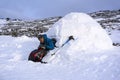 Smiling hiker offers a mug of tea while sitting in a snowy hut igloo in winter Royalty Free Stock Photo