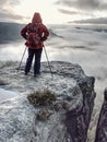 Hiker with red backpack and trekking sticks walking at edge