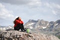 Hiker in red resting sitting in the top of a mountain