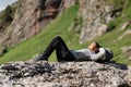 Hiker resting lying on a rock in the mountain