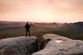 Hiker on sharp cliff in rocky empires park, watching over misty and foggy morning gulch to horizon.