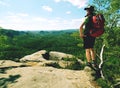 Hiker in shorts wear cowboy hat and red back pack, stay on rock