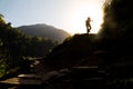 Hiker in silhouette hiking at highland towards sunrise. Lens flare intended