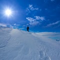 hiker silhouette on snowbound mount slope under a sparkle sun Royalty Free Stock Photo